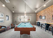 Thumbnail 40 of 47 - A pool table is in the middle of a room with a brick wall and a bar area.