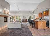 Thumbnail 44 of 47 - A modern kitchen with a grey couch and wooden cabinets.