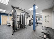 Thumbnail 34 of 47 - A gym with a variety of equipment including a squat rack, a leg press machine, and a bench.
