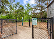 Thumbnail 27 of 34 - A dog park is enclosed by a black fence with a sign on it.