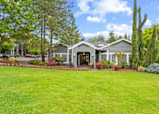 Thumbnail 17 of 34 - A house with a grey roof and a green lawn in front.