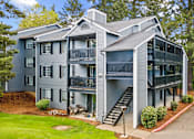 Thumbnail 31 of 34 - A grey two story apartment building with a balcony on the second floor.