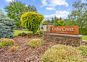 Thumbnail 34 of 34 - A sign for Cedar Crest Apartments is surrounded by shrubbery and trees.