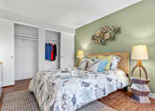 Thumbnail 8 of 34 - A bedroom with a large bed and a lamp on a side table.