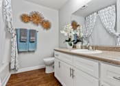 Thumbnail 10 of 34 - A bathroom with a toilet, sink, and a mirror.