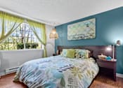 Thumbnail 11 of 34 - A bedroom with a bed, nightstand, and window with curtains.