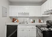 Thumbnail 5 of 25 - Sandy Springs, GA Apartments – Celebration at Sandy Springs – A white kitchen with a black dishwasher and stove.