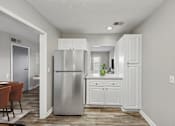 Thumbnail 6 of 25 - Pet-Friendly Apartments in Sandy Springs– Celebration at Sandy Springs – A kitchen with a refrigerator, cabinets, and a dining table.