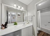 Thumbnail 10 of 25 - Pet-Friendly Apartments in Sandy Springs– Celebration at Sandy Springs – A bathroom with a white counter and a mirror above it.