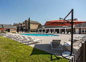 Thumbnail 16 of 31 - Pet-Friendly Apartments in Oak Ridge, TN – Centennial Village – a swimming pool with lounge chairs and umbrellas