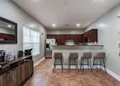 Thumbnail 27 of 31 - Pet-Friendly Apartments in Oak Ridge, TN – Centennial Village – a kitchen with a bar and stools in the clubhouse