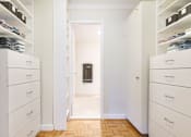 Thumbnail 25 of 66 - A hallway with white cabinets and drawers on both sides leading to a bathroom.