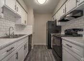 Thumbnail 25 of 28 - an empty kitchen with white cabinets and black appliances