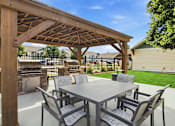 Thumbnail 34 of 47 - A wooden pergola with a table and chairs underneath it.