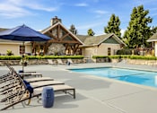 Thumbnail 2 of 47 - A pool with sun loungers and a blue umbrella in front of a house.