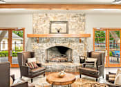 Thumbnail 35 of 47 - A living room with a stone fireplace and a picture of a deer above it.
