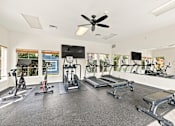Thumbnail 31 of 47 - A spacious gym with a variety of equipment including treadmills, stationary bikes, and weight machines.