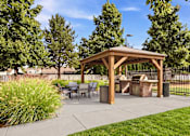 Thumbnail 4 of 47 - A wooden gazebo is surrounded by trees and a fence.