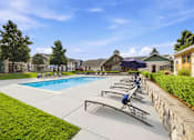 Thumbnail 25 of 47 - A swimming pool with sun loungers and a stone wall.