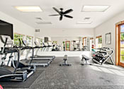 Thumbnail 3 of 47 - A spacious gym with treadmills, elliptical machines, and a fan.