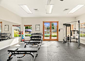 Thumbnail 32 of 47 - A gym with a row of treadmills and a row of dumbbells.