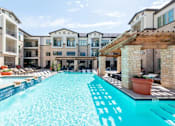 Thumbnail 5 of 17 - A large swimming pool in front of apartment buildings.