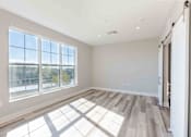 Thumbnail 9 of 22 - Spacious studio apartment at Creekline at Fairfield in Fairfield, CT with oversized windows and double sliding barn doors creating privacy between the living area and sleeping space.