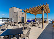 Thumbnail 17 of 22 - Rooftop patio with shaded pergola, outdoor tables, and resident gathering space at Creekline at Fairfield, Fairfield CT.