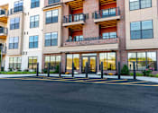Thumbnail 1 of 22 - Front entrance of Creekline at Fairfield apartments in Fairfield, CT featuring a modern brick-and-siding exterior, glass entry doors, and balcony residences above.