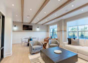 Thumbnail 13 of 22 - A modern living room with Community lounge with cozy seating, exposed wood ceiling beams, and bright window views at Creekline at Fairfield apartments, Fairfield CT. 