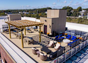 Thumbnail 19 of 22 - Aerial view of the rooftop terrace at Creekline at Fairfield apartments in Fairfield, CT featuring a pergola, outdoor dining tables, lounge seating, and resident gathering areas.