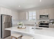 Thumbnail 3 of 22 - Open-concept kitchen featuring quartz-style countertops, large island seating area, and stainless steel appliances at Creekline at Fairfield apartments, Fairfield CT.