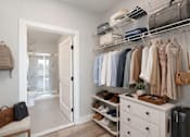 Thumbnail 6 of 22 - Walk-in closet with shelving leading into an en-suite bathroom at Creekline at Fairfield in Fairfield, Connecticut.