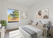 Thumbnail 8 of 19 - Pet-Friendly Apartments in Austin, TX – Huntington Meadows – A bedroom with a large bed and a window overlooking a tree.