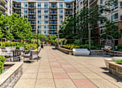 Thumbnail 25 of 25 - A patio with a table and chairs is surrounded by trees and buildings.
