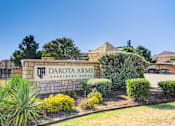 Thumbnail 20 of 20 - A sign for Dakota Arms Apartment Homes is surrounded by landscaping.