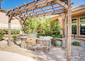 Thumbnail 18 of 20 - A wooden pergola is over a stone bench with a planter underneath.
