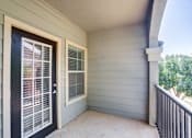 Thumbnail 15 of 20 - A balcony with a black door and a window with white blinds.