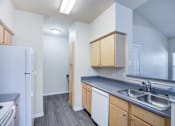 Thumbnail 8 of 20 - A kitchen with a white refrigerator, wooden cabinets, and a grey countertop.