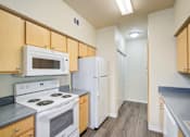 Thumbnail 4 of 20 - A kitchen with white appliances and wooden cabinets.