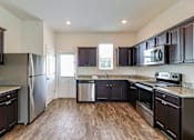 Thumbnail 66 of 75 - A kitchen with dark wood cabinets and stainless steel appliances.