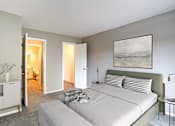 Thumbnail 5 of 24 - A bedroom with a bed, nightstand, and a painting on the wall.