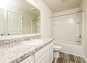 Thumbnail 17 of 38 - A bathroom with a marble countertop and white fixtures.