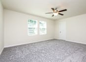 Thumbnail 18 of 38 - A room with a ceiling fan and carpeted floor.