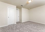 Thumbnail 15 of 38 - A room with two doors and carpeted floor.
