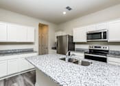 Thumbnail 24 of 38 - A kitchen with granite countertops and stainless steel appliances.