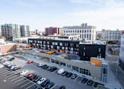 Thumbnail 26 of 29 - A parking lot with cars and a building in the background.