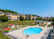 Thumbnail 14 of 31 - Pet-Friendly Apartments in Oak Ridge, TN – Centennial Village – an aerial view of an outdoor pool with chairs and umbrellas