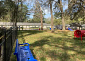 Thumbnail 24 of 28 - Addison Lane Apartment homes in Gainesville Florida photo of photo of a large grassy area with a swing set and a bench in front of a fence