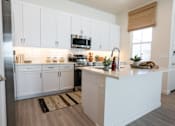 Thumbnail 11 of 16 - A kitchen with white cabinets and a wooden countertop.